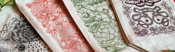 Cotton Canvas Lunch Bags are printed with red, green, black, and purple inks featuring botanical and animal designs by Fennec Design