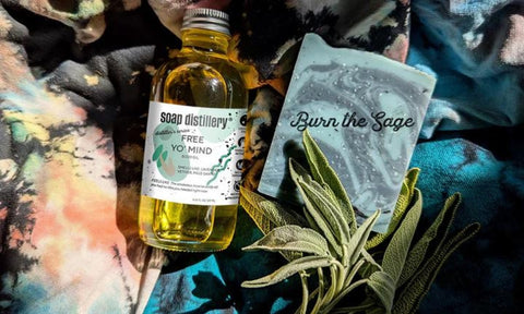 Soap Distillery's body oil and soap lay against a dark tie dyed background